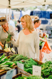 Melanee at the market holding a bunch of greens