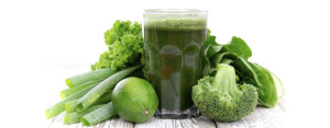 A green smoothie surrounded by green vegetables