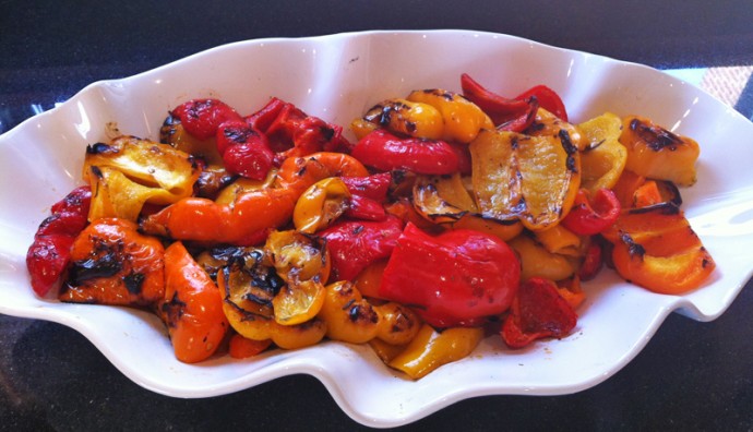 Grilled red and yellow peppers on a white wavy plate