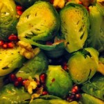 Steamed Brussels sprouts cut in half and sprinkled with pomegranate seeds and walnuts