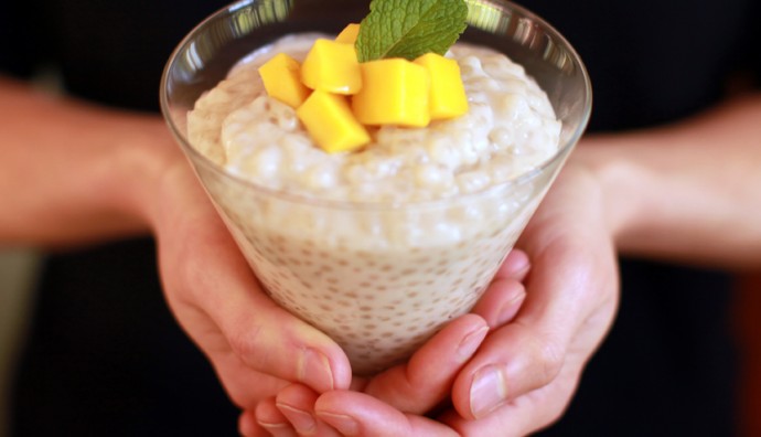 Coconut and tapioca pudding with mango on top in a glass
