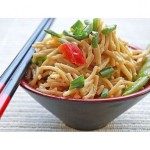 Asian noodles with vegetables and peanut sauce in a black bowl