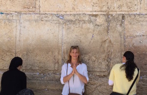 Melanee standing against a wall in Jerusalem with praying hands