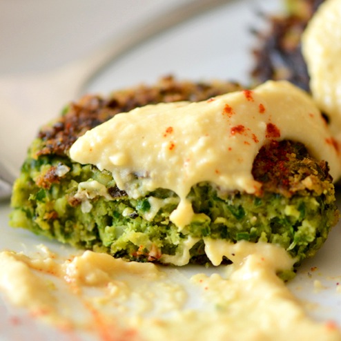 A green falafel piece with hummus on it