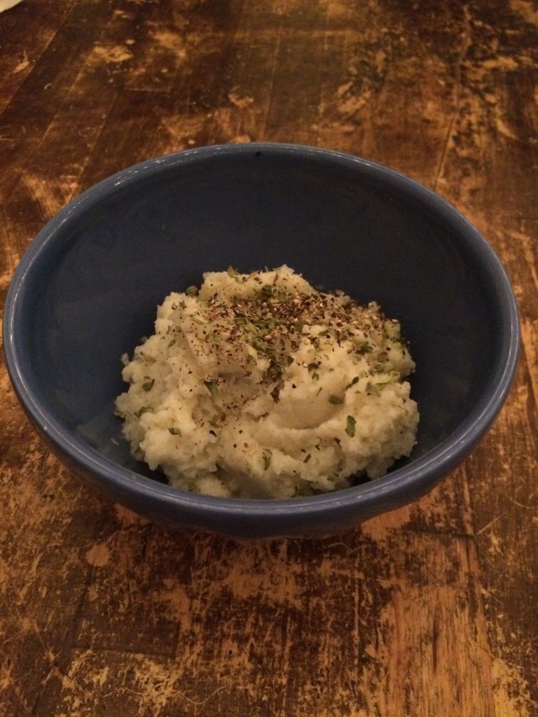 Cauliflower mash with sprinkled spices in a black bowl