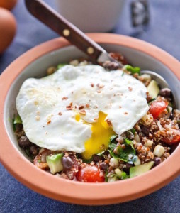 A bowl of quinoa with vegetables and a soft boiled egg on top