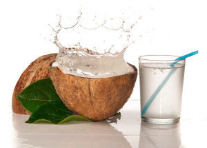 A glass with coconut water next to a coconut open in half