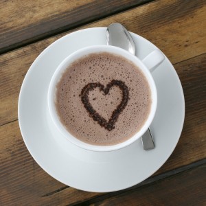 A cup of foamy hot chocolate with a heart drawn on top