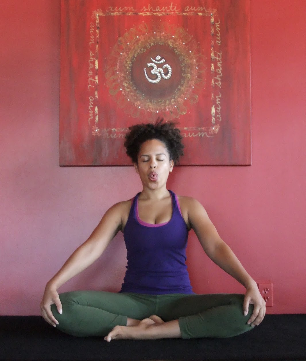 A woman sitting in the Lotus pose practicing Sitali breath
