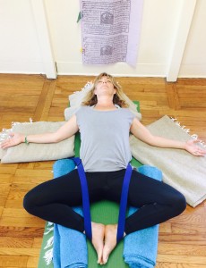 Melanee laying on a yoga mat in the Supported Bound Angel Pose