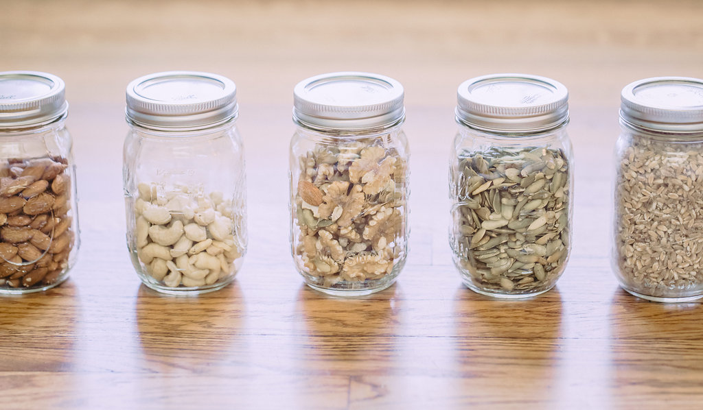 Five small jars with different nuts and seeds.