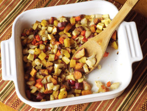 Roasted diced root vegetables in a white pan