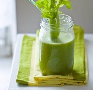 Green ginger celery juice in a small jar on a green kitchen towel
