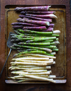 Three types of asparagus on a baking sheet